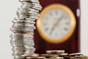 Pièces de monnaies et horloge illustrant un article sur l'Assurance-Vie